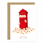 Ευχετήρια κάρτα Gold Love Mails της All The Ways To Say με κόκκινο γραμματοκιβώτιο γεμάτο ερωτικά γράμματα και χρυσές λεπτομέρειες.